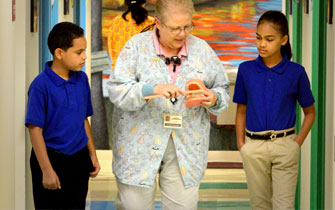 Nurse showing device to attentive students in hallway.